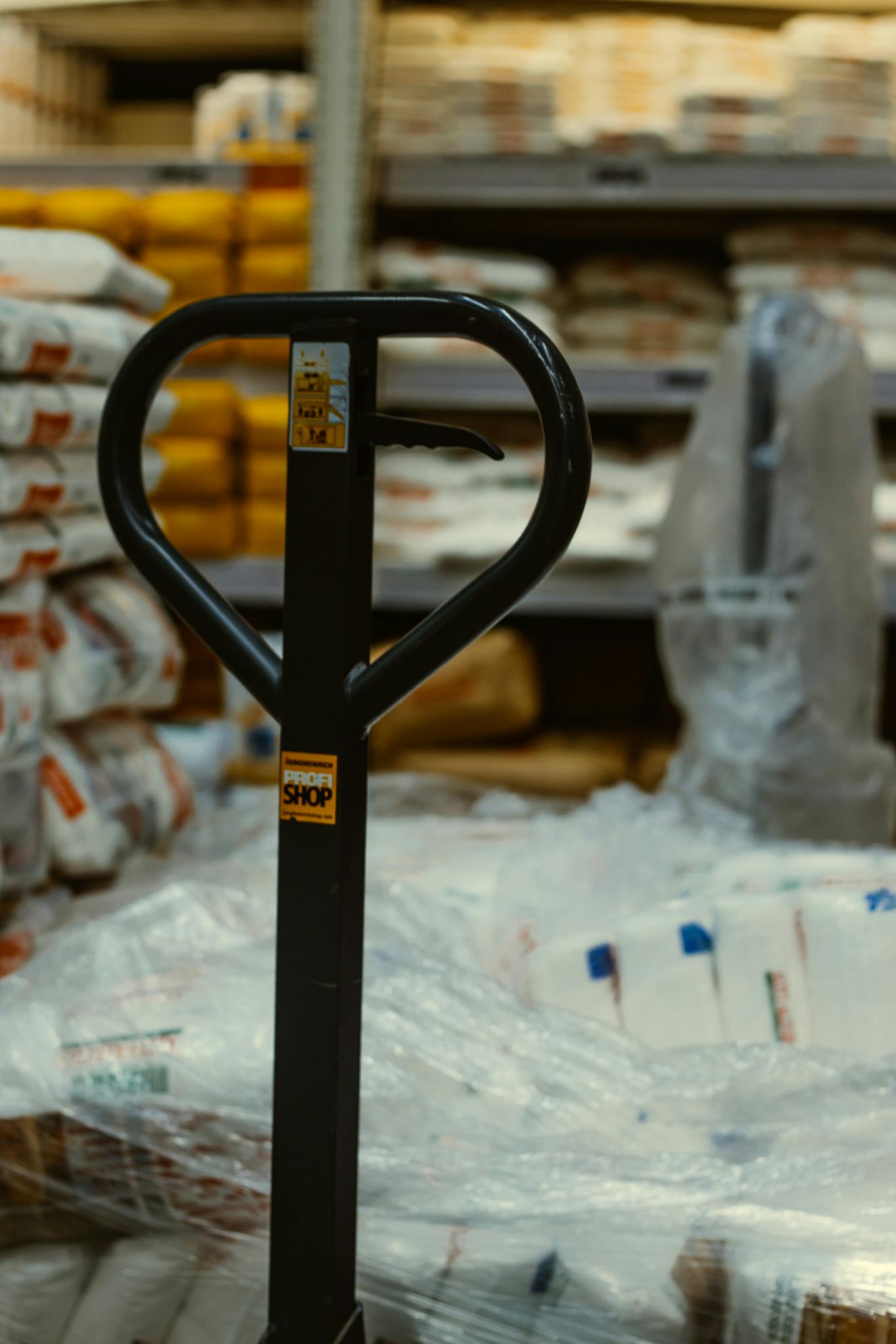 Pallet truck in an industrial warehouse with stacked goods.